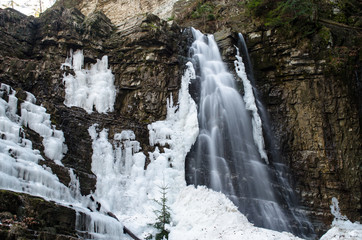 Fototapeta na wymiar Winter view of a waterfall in the rocky canyon