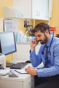Doctor sitting at his desk and talking on phone
