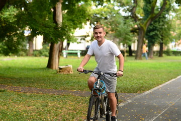 Obraz premium Blonde attractive young man cycling in the park 