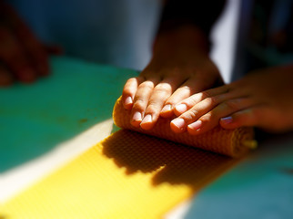 making candle from honey bee wax plate at market.