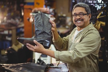 Portrait of smiling shoemaker holding a leather boot - Powered by Adobe