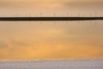 Sunset over the wind farm with reflection on lake