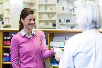 Fototapeta premium Pharmacist giving medicine box to customer