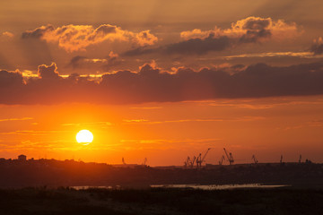 Obraz na płótnie Canvas Sunset over an industry harbor with cranes