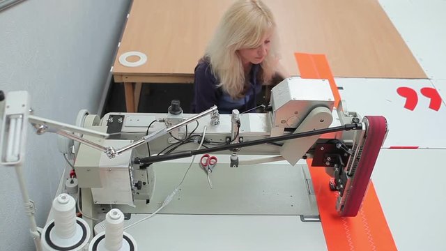 Seamstress monitors process of sewing machine work