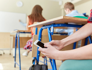 student boy with smartphone texting at school