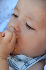 Retrato de un bebe comiendo bizcocho.