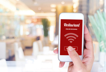 Smart phone with online booking on screen over blur restaurant b