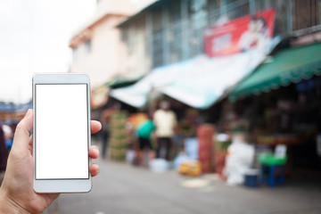 Business conceptual- Focused on left hand holding mobile at local market at Bangkok,Thailand in blurred background