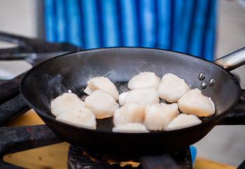 close up of scallops frying in cast iron pan