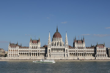 Fototapeta na wymiar Neo-Gothic building of Hungarian Parliament, a cruise ship on the River Danube in sunlight, Budapest