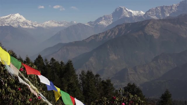 Colorful praying flags flutter in wind on Poon Hill with a background of beautiful Dhaulagiri and Annapurna mountain ranges in Nepal