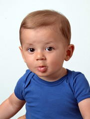 Retrato de un hermoso bebe rubio con camisa azul en fondo blanco
