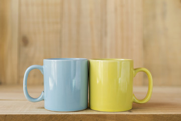 Blue and yellow ceramic coffee mug with wood background