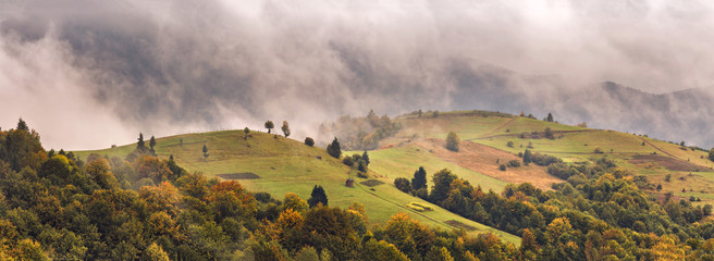 Autumn foggy mountain panorama. Fall rain and mist