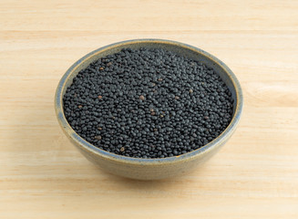Black beluga lentils in a stoneware bowl on a wood table.