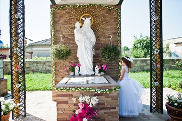 Portrait of cute little girl on white dress and wreath of first holy communion background monument...
