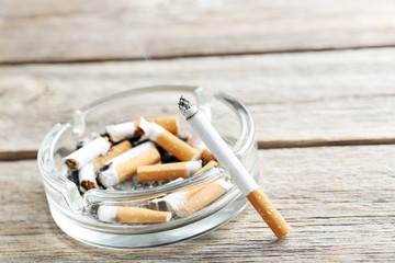 Cigarette with ash on grey wooden table