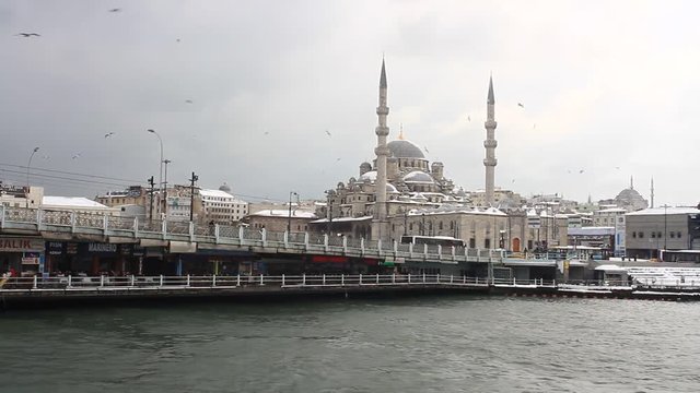 Yeni Mosque and Galata Bridge in the snow. Valide Sultan Mosque in the distance