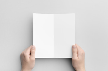 DL Bi-Fold Brochure Mock-Up - Male hands holding a blank bi-fold on a gray background.