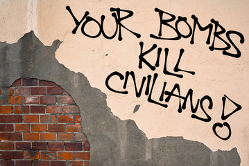 Your Bombs Kill Civilians - Handwritten graffiti sprayed on wall, anarchist aesthetics - protest...