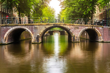 Old Bridge over a Canal in Amsterdam and Reflection in Water © alpegor