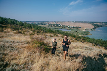 Young couple running outdoor. Male and female jogging in the countryside near the lake