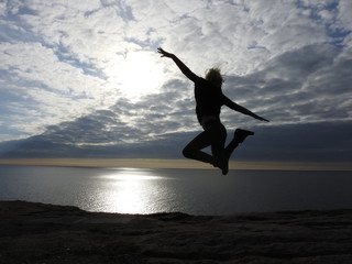 Fototapeta na wymiar Woman jumping in the sunset at the tip of Norway