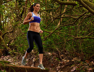 Young woman girl trail running jogging in green forest nature park