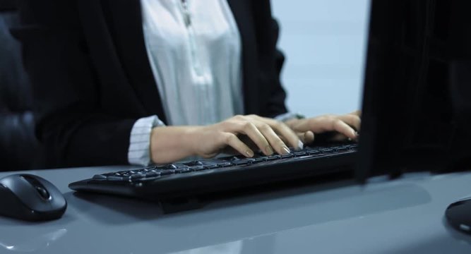 4K: Eine junge Frau schreibt auf der Computertastatur. Ein Medium shot der Tastatur und der H&auml;nde.