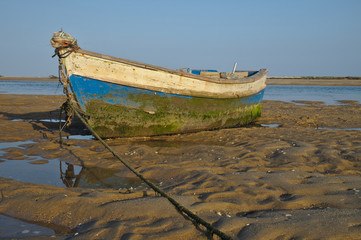 Old wooden fishing boat resting on the beach sand in Portugal