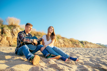 young caucasian couple with guitar on beach