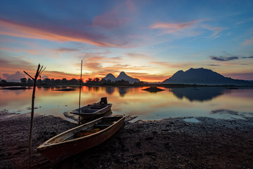 Beautiful majectic sunrise by the lakeside with fishing boats. Nature landscape.