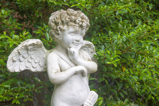 Cupid statue in the garden with leaf background