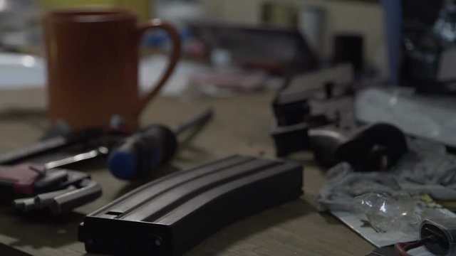 Man repairing a machine gun. Table with tools for repair of weapons. Military rifle