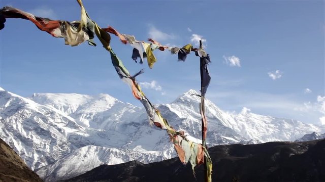 High snow-capped gorgeous white himalayan mountain range with colorful praying flags fluttering in wind, Annapurna circuit trek