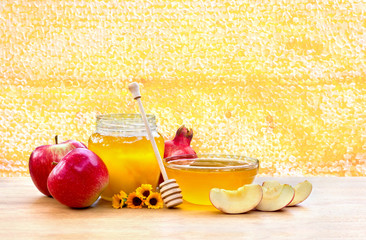 Honey, red apples, garnets and calendula flowers on wooden table on  background honeycombs with full cells of honey sealed with wax