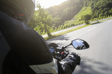Motorradfahrer fährt auf Straße im Sommer