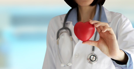 Positive female doctor standing with stethoscope and red heart s