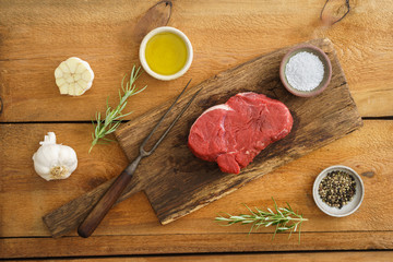 Uncooked fillet steak on wooden board on wood