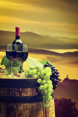 Fototapeta na wymiar Red wine with barrel on vineyard in green Tuscany, Italy