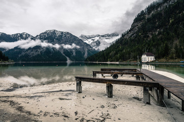 Wooden pier in Plansee lake located in Austria a cloudy and foggy day. Horizontal composition