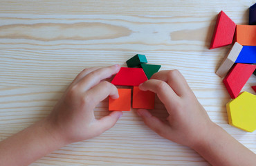 A child plays with colored blocks constructs a model on a light