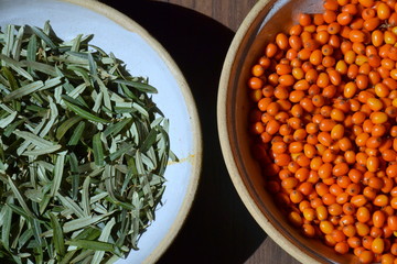 Sea buckthorn fruits and leaves in two ceramic bowls