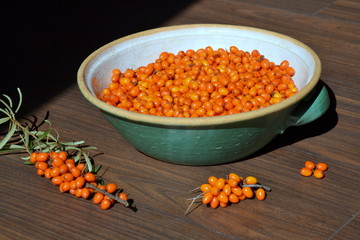 Sea buckthorn fruits and leaves in a large ceramic bowl