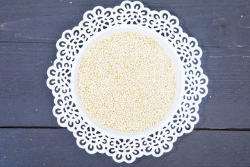 White quinoa on white plate on black wooden background