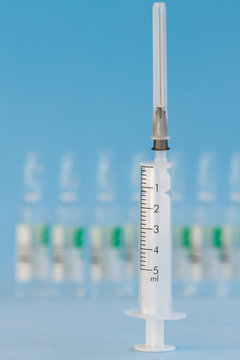 Five ml syringe on a blue background.