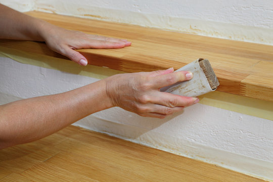 Worker Sanding Plank At Stairs Using Sand Paper