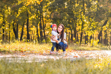 Fototapeta premium Little girl and her mother playing in the autumn park
