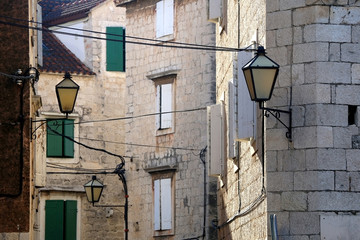 Traditional mediterranean street with stone houses, picturesque windows and retro lamps. In Trogir, Croatia. Trogir is popular touristic destination and UNESCO World Heritage Site.
